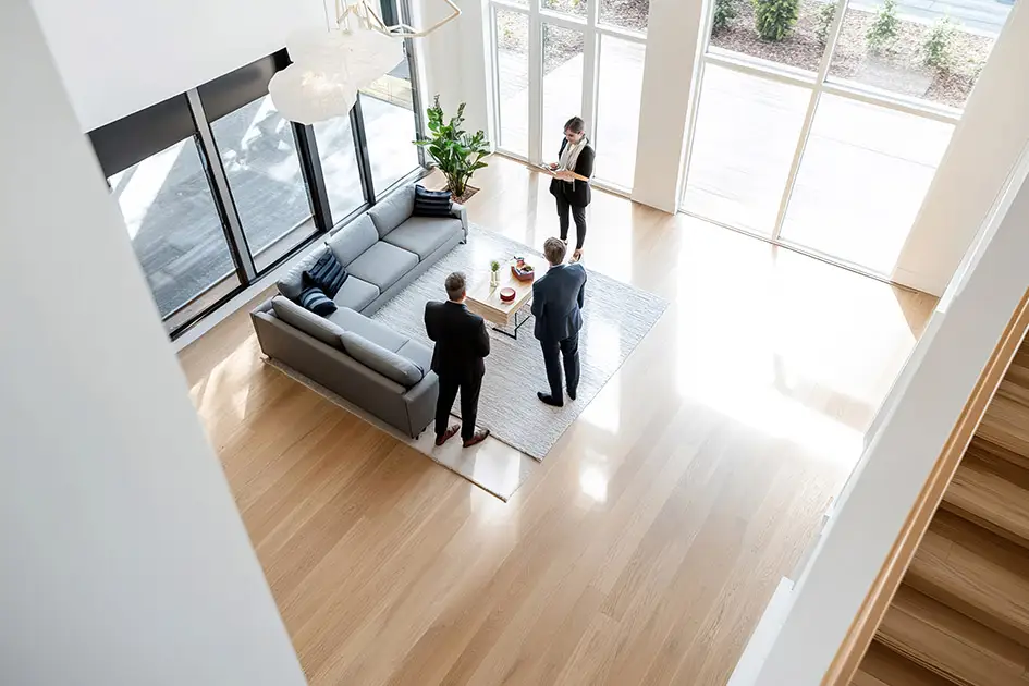 Interessenten stehen im großen Wohnzimmer einer modernen Villa